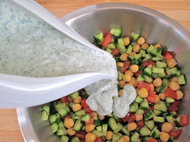 Pouring dressing over chickpea salad.