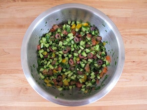 Tossing salad with dressing in a mixing bowl.