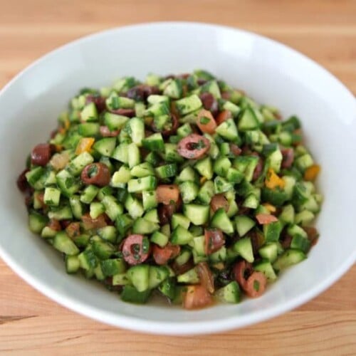 Fresh Israeli salad with diced tomatoes, cucumbers, onions, and parsley, drizzled with olive oil and lemon juice