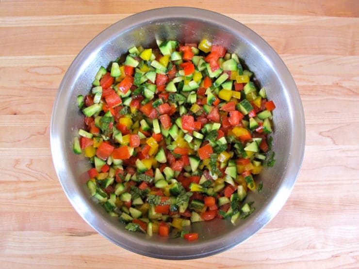 Chopped salad tossed with dressing in a mixing bowl.