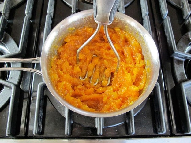 Using a potato masher on simmered apricots.
