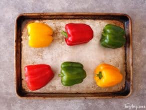 Colorful bell peppers on baking sheet.