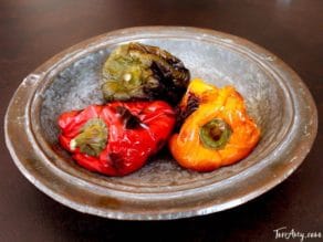 Green, red and yellow roasted bell peppers in silver bowl.