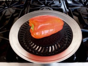 Red bell pepper roasting on grill pan.