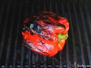 Roasted bell peppers on a grill with charred skin, vibrant colors
