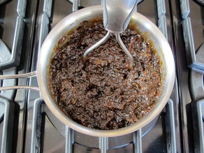 Using a potato masher on simmered prunes.