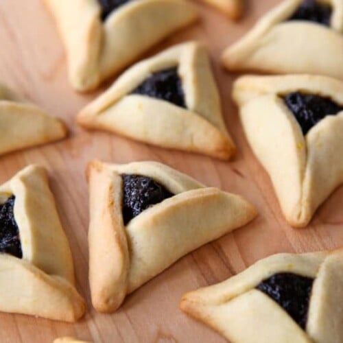 Prune-filled hamantaschen cookies on a wooden background.