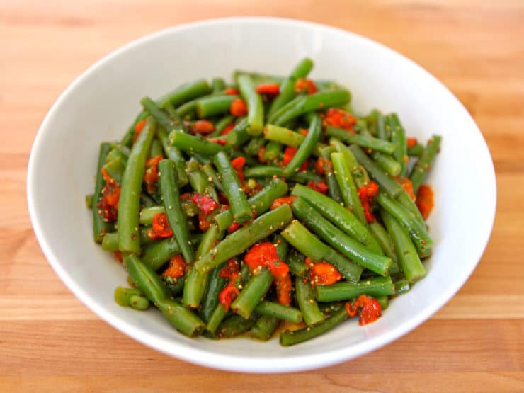 A vibrant mix of crisp green beans and colorful pepper on a white bowl