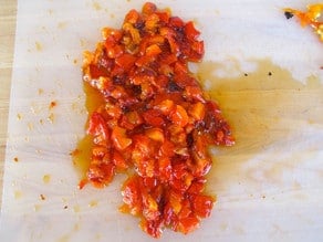 Dicing a roasted red pepper on a cutting board.