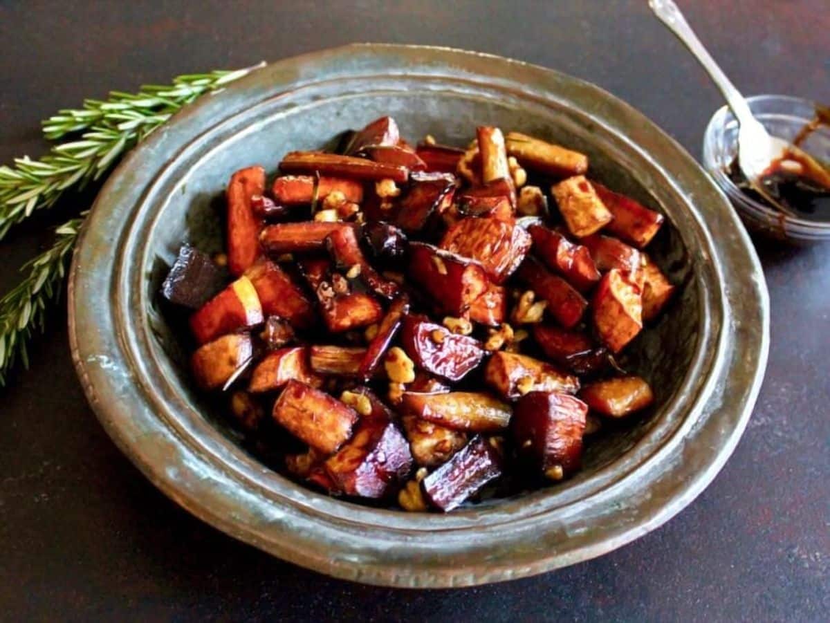 Rustic plate of Roasted Rosemary Balsamic Tzimmes, rosemary sprigs in background.