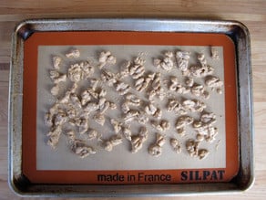 Walnuts spread out on a lined baking sheet.