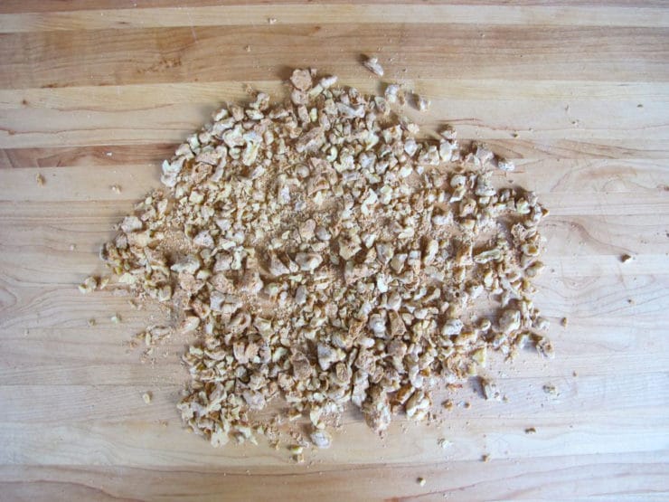 Roughly chopped walnuts on a cutting board.