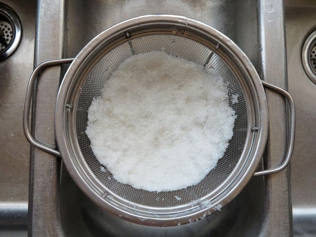 Draining coconut in a strainer.