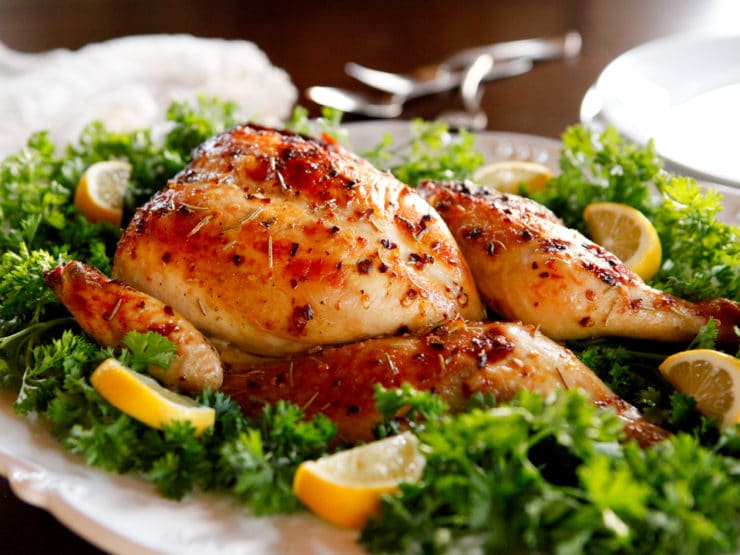 A plate with a chicken dish garnished with lemons and parsley