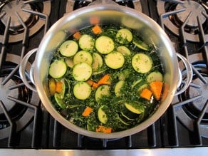 Diced vegetables covered with water in a stockpot.
