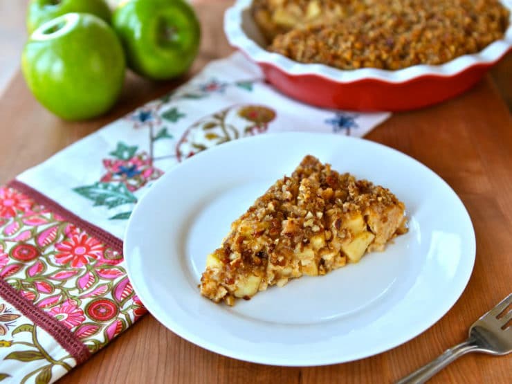 A slice golden-brown pie with a flaky crust, filled with sweet apple slices and crunchy pecans