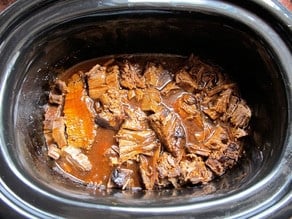 Sliced beef brisket returned to the slow cooker.