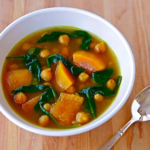 Butternut Squash and Chickpea Soup served on a white bowl with spoon on a table