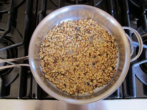 Chopped walnuts toasting in a pan.