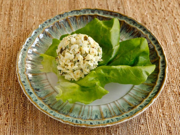 A fresh lettuce leaf sits on a plate alongside freshly made egg salad