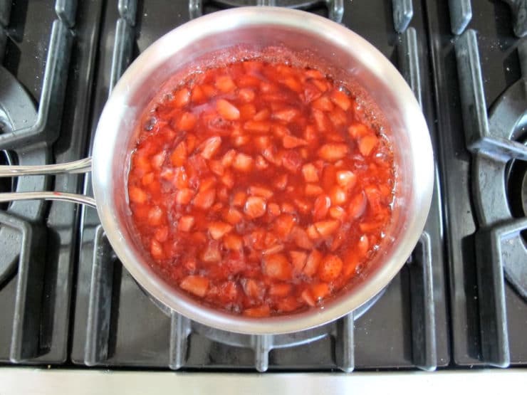 Thickened strawberry topping in a saucepan.
