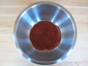 Tomato sauce and seasoning in a mixing bowl.