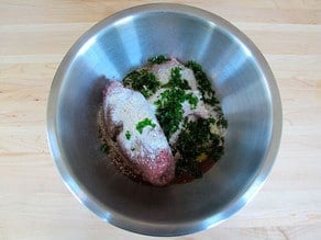 Ground meat and seasoning in a mixing bowl.