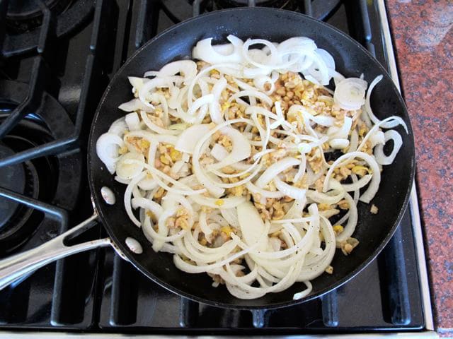 Chicken skin and onions in a skillet.