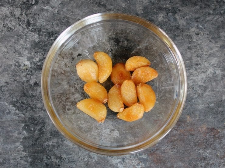 Glass bowl filled with whole roasted garlic cloves.