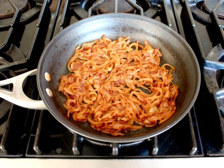 Caramelized onions in large skillet on stovetop.