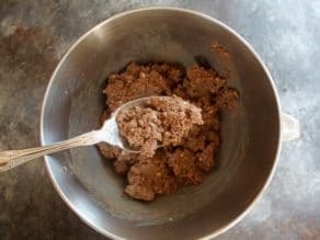 Steel mixing bowl with ground chopped liver, spoon scooping up chopped liver.