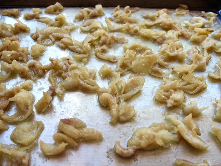 Chicken skin browning and curling on baking sheet.