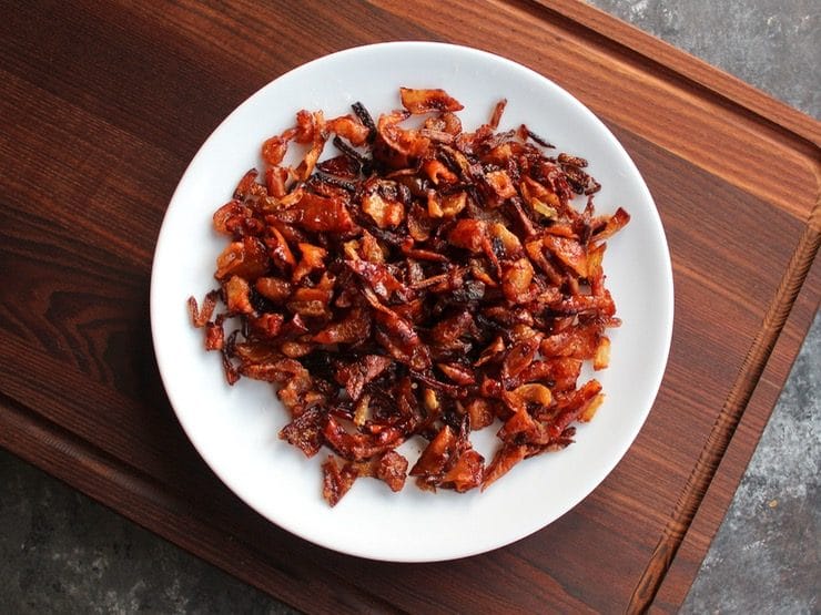 Gribenes on a white plate on wooden cutting board.