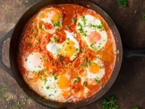 Horizontal shot of cast iron pan filled with Shakshuka.