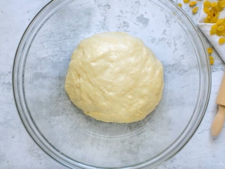 Dough resting in a smooth ball in oiled glass bowl.