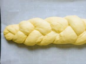 Braided challah dough on parchment-lined baking sheet.