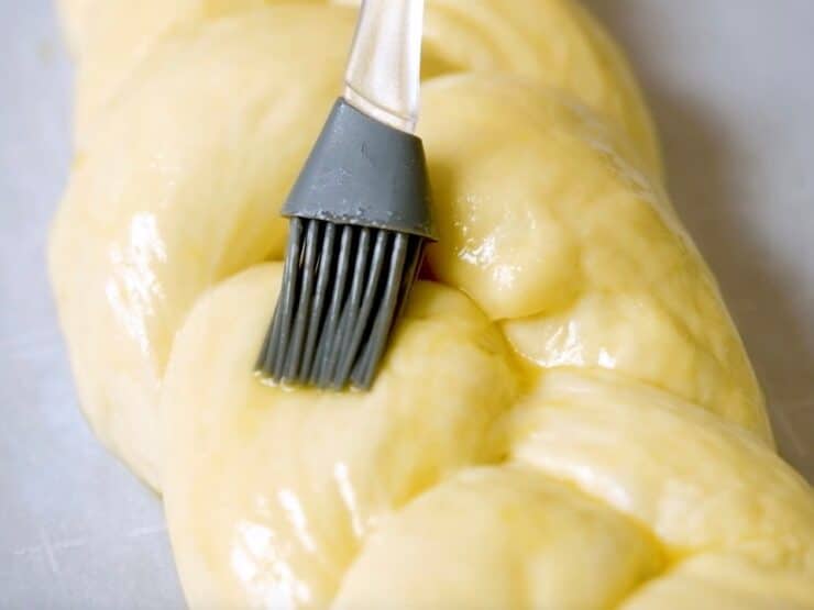 Silicone brush brushing challah braid with egg wash.