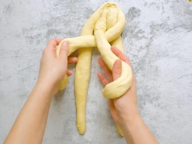 Overhead shot of two hands beginning to braid a 4 strand challah.