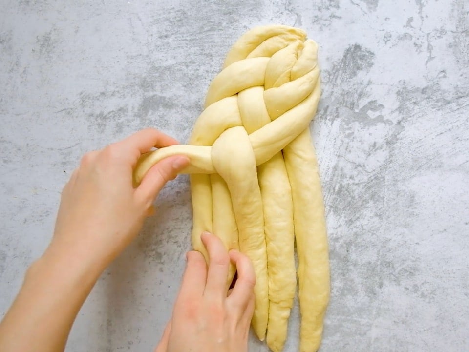 Overhead shot of two hands braiding a 6 strand challah.