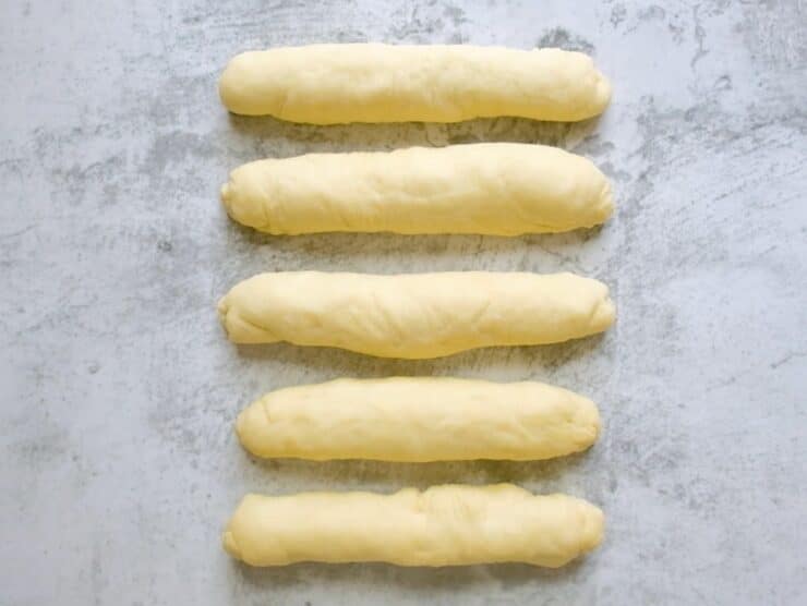 Five short thick dough strands on concrete countertop.