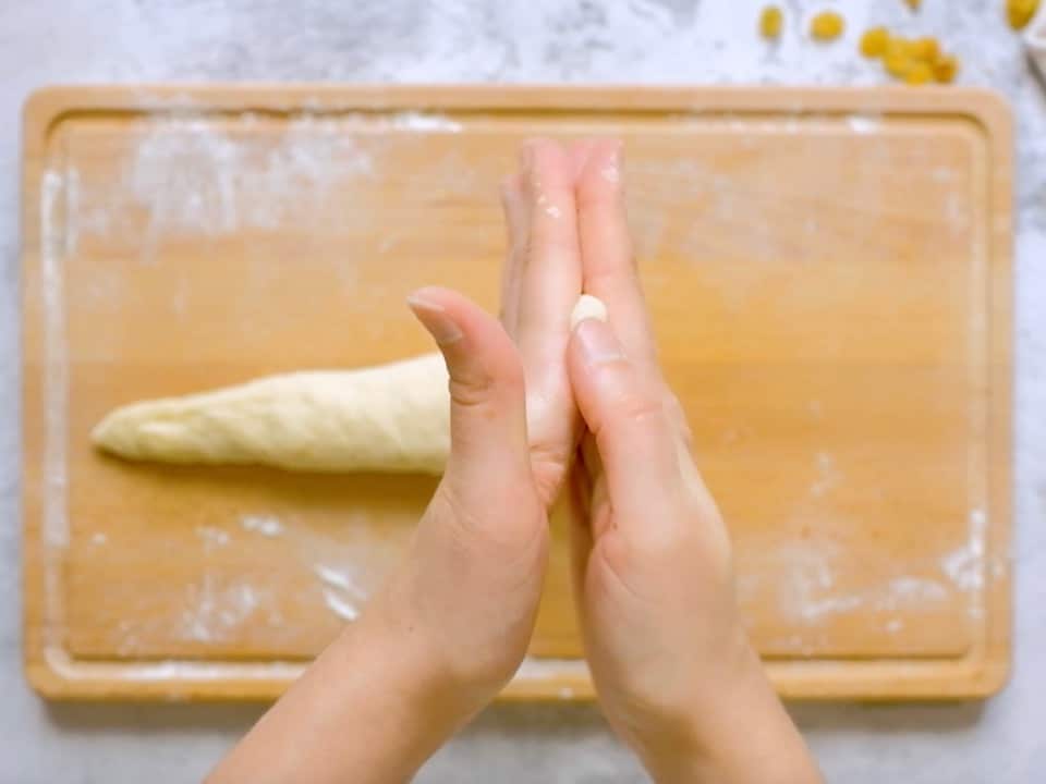 Overhead shot of two hands rolling the end of the challah strand into a taper.
