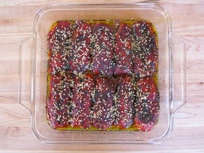 Toasted sesame seeds on stuffed peppers in a baking dish.