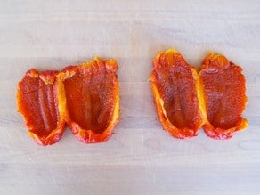 Roasted red peppers sliced open in half.