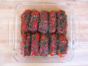 Herbs sprinkled over stuffed peppers in a baking dish.