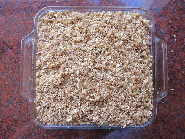 Crumble topping added to apples in baking dish.