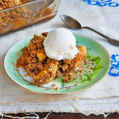 A delicious Oat Nut Apple Crisp dessert with a golden brown crumble and icecream topping served in a white ceramic dish