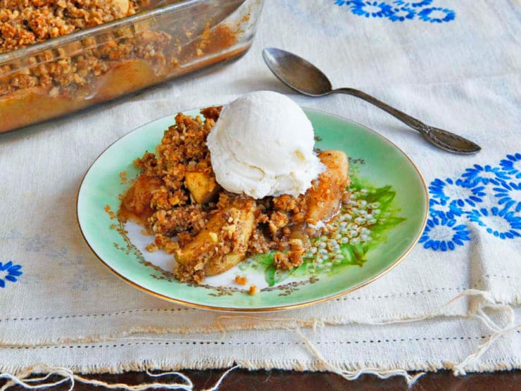 A delicious Oat Nut Apple Crisp dessert with a golden brown crumble and ice-cream topping served in a white ceramic dish