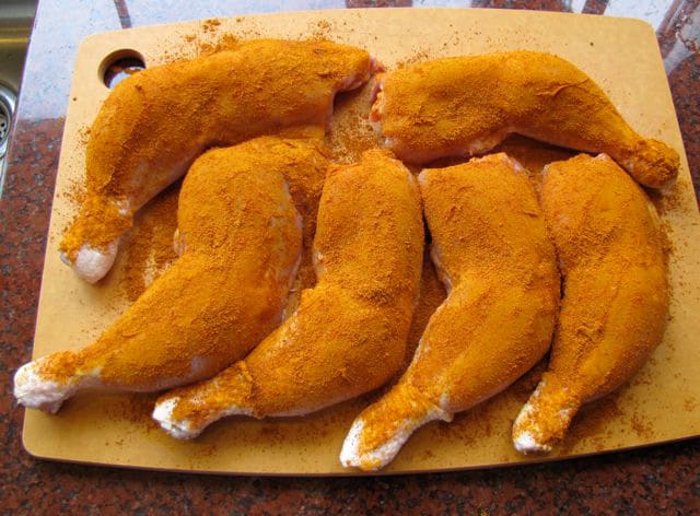 Spices rubbed into chicken quarters.