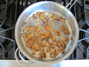 Mushrooms sauteing in a skillet.