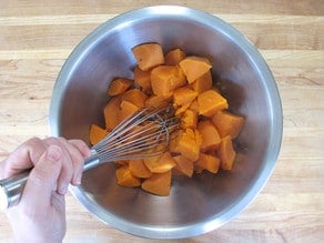 Mashing sweet potatoes in a mixing bowl.